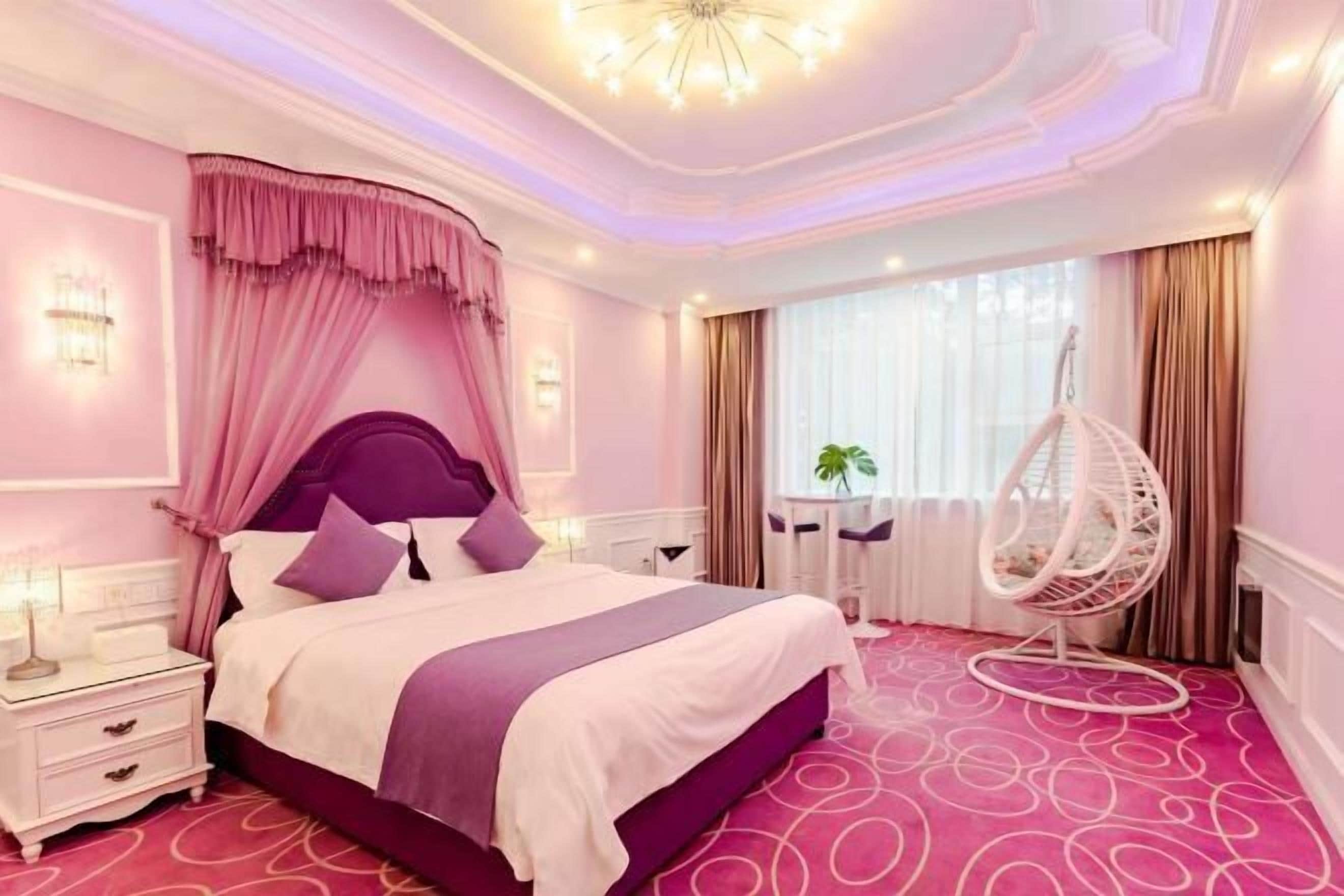 A bedroom with a large bed, a nightstand, a hanging chair, and a window with curtains.