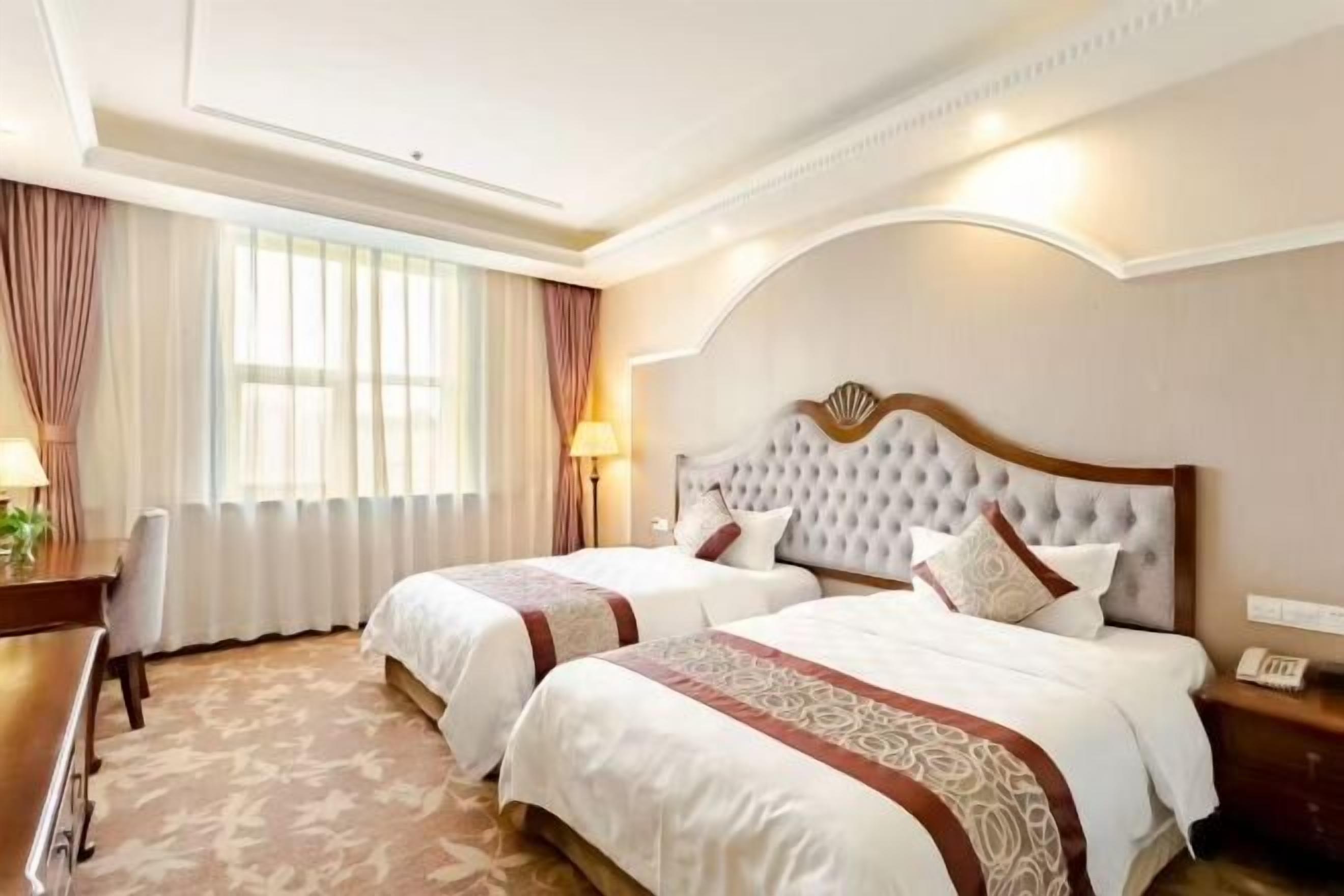 Une chambre d’hôtel avec deux lits, un bureau et une chaise.
