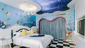 A bedroom with a checkered floor, a bed with white bedding, a nightstand, a chandelier, and a mural of an underwater scene. - Hawaii Hotel (Leshan Jiaxing Road Food Street) (Leshan)