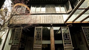 Un edificio tradicional de madera con múltiples ventanas y un porche cubierto.
