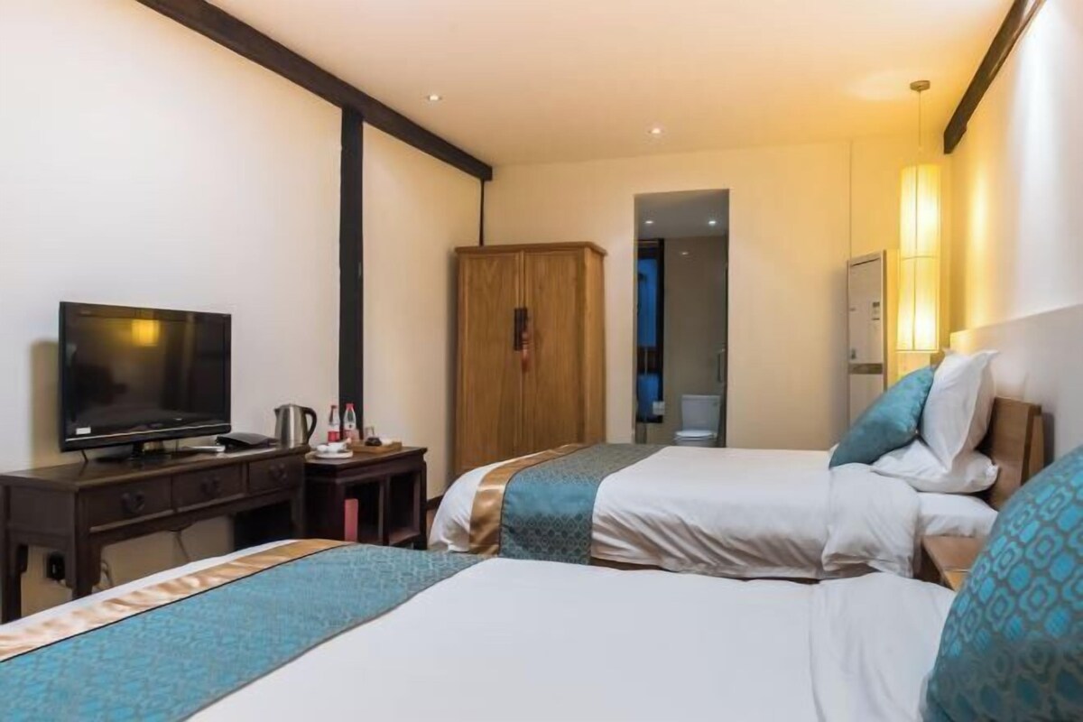 Een hotelkamer met twee bedden, een televisie, een bureau en een kledingkast.