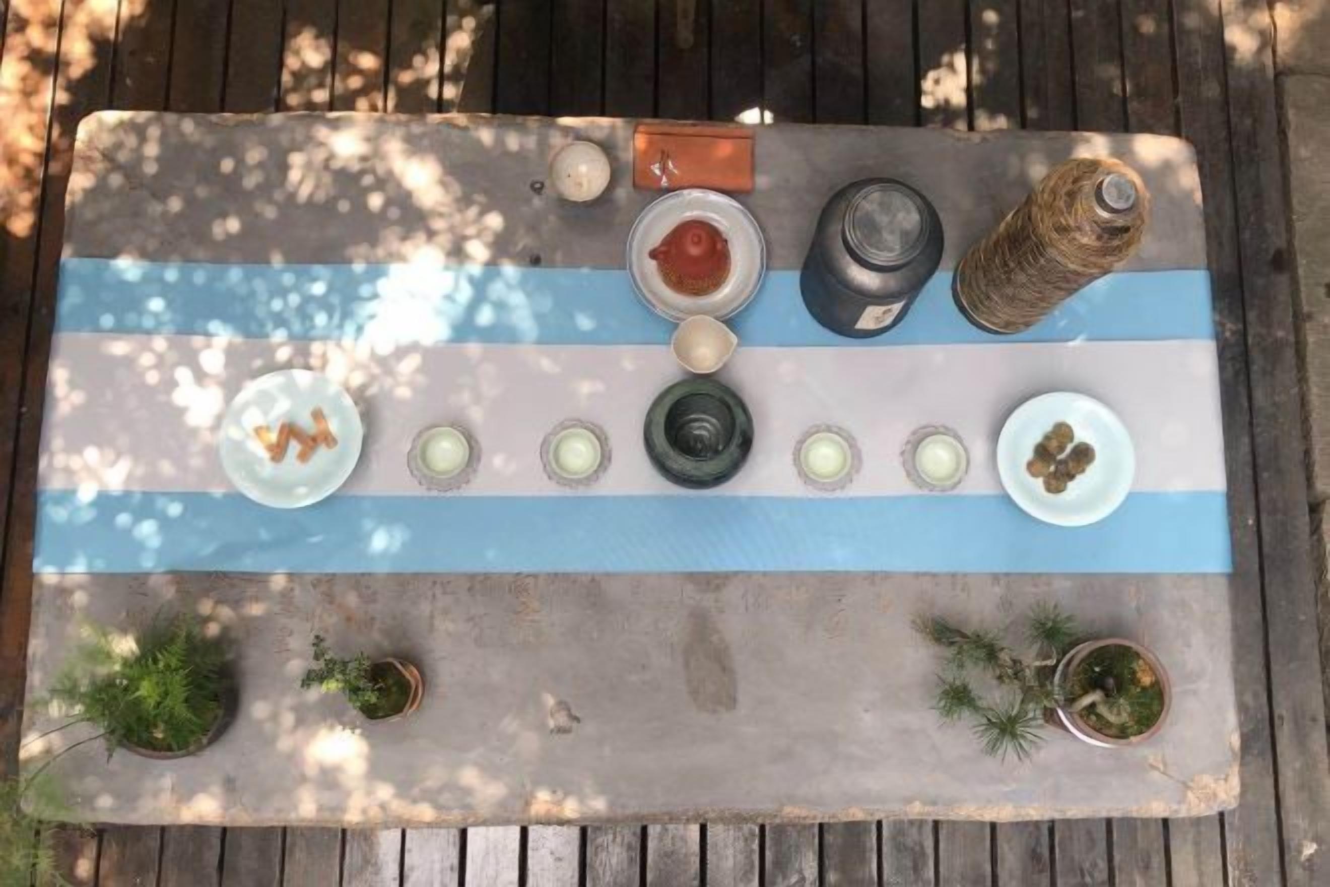 Una mesa de madera con diseño a rayas, varios objetos pequeños y plantas en macetas.