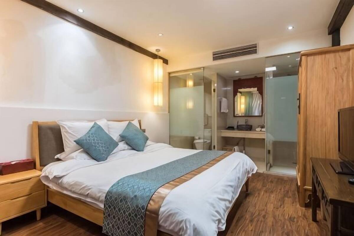 Ein Hotelzimmer mit Bett, Nachttisch und einem Holzschrank.
