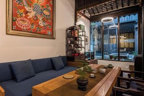 Una habitación tradicional con una mesa de madera, un sofá azul y un ventanal con vistas.