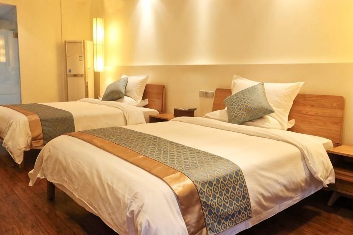 Une chambre d’hôtel avec deux lits, des têtes de lit en bois et des tables de chevet.