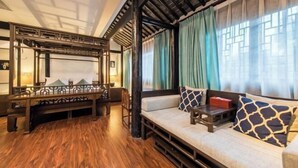Una habitación tradicional con suelo de madera, un sofá con cojines estampados, un banco y una barandilla decorativa.
