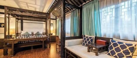 A traditional room with a wooden floor, a sofa with patterned cushions, a bench, and a decorative railing.