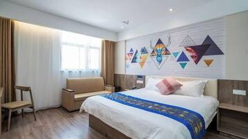 A hotel room with a large bed, a sofa, a desk, and a window with curtains.
