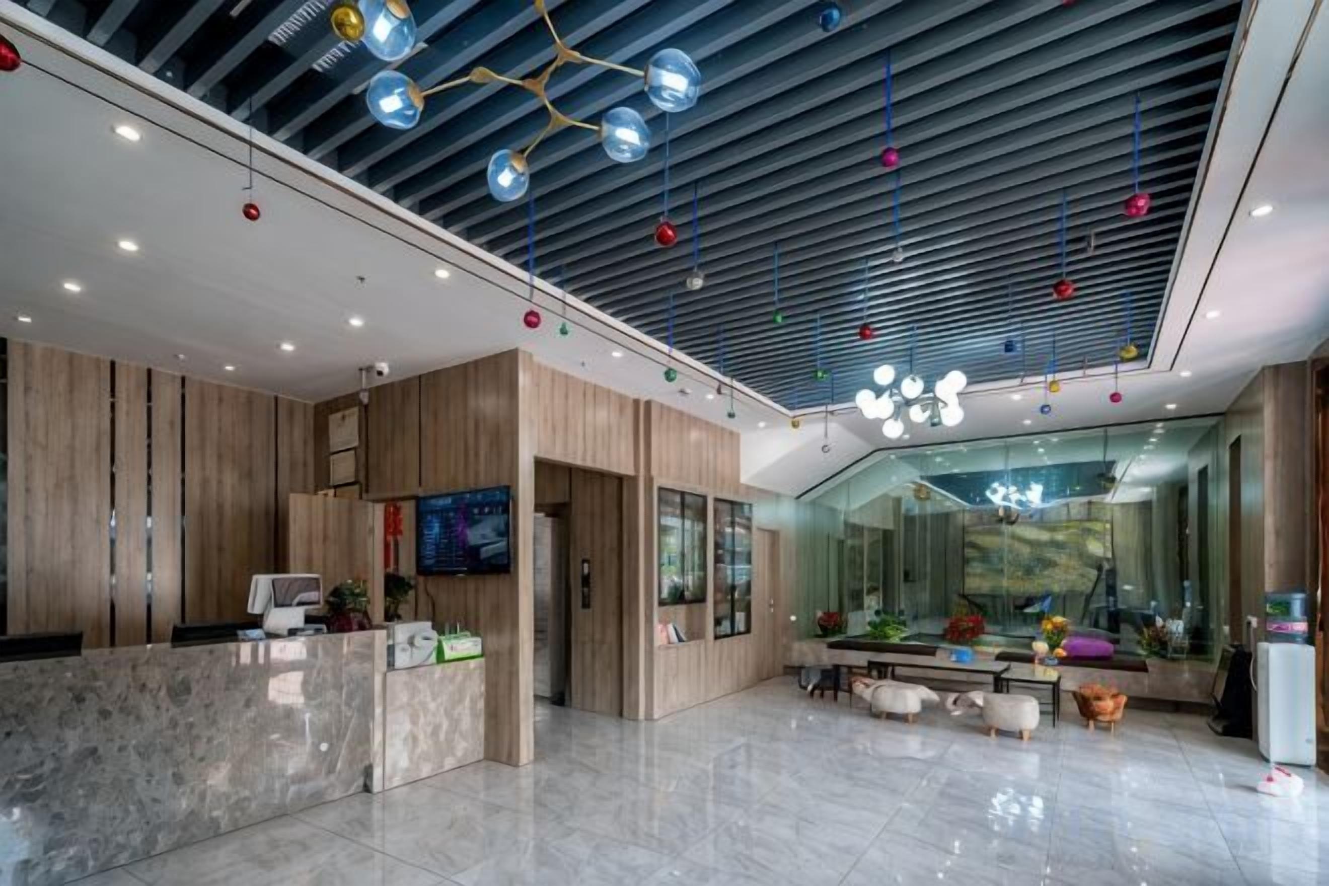 A modern hotel lobby with a reception desk, seating area, and a large window offering a view.