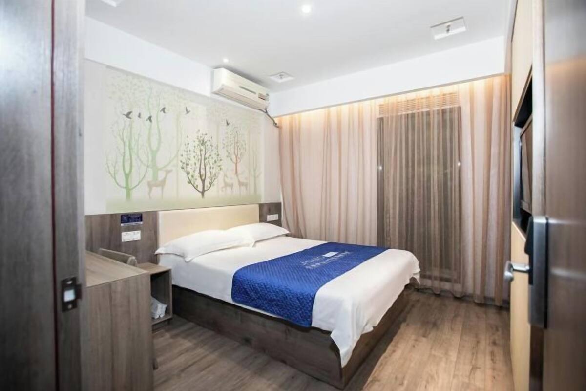 Ein Hotelzimmer mit einem Bett, einem Schreibtisch, einem Sessel, einem Fernseher und einem Fenster mit Vorhängen.