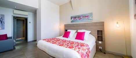 A modern hotel room with a large bed, a sofa, and a painting on the wall.