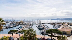 Un puerto deportivo con numerosas embarcaciones amarradas, rodeado de palmeras y edificios.