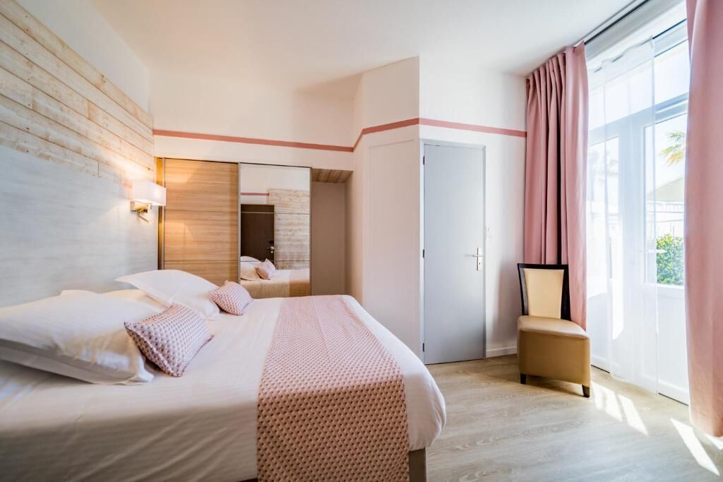Een hotelkamer met een groot bed, een stoel, een spiegel en een deur.