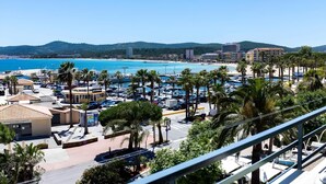 Un complejo turístico frente al mar, con puerto deportivo, playa y palmeras.