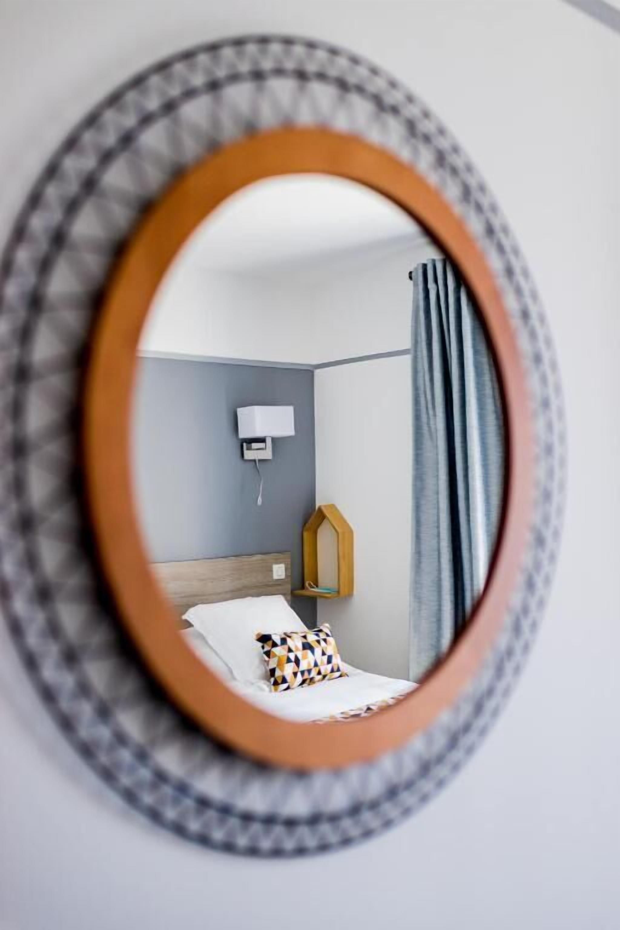 Ein Hotelzimmer mit einem Bett, einem Nachttisch, einer Lampe und einem an der Wand montierten Fernseher.