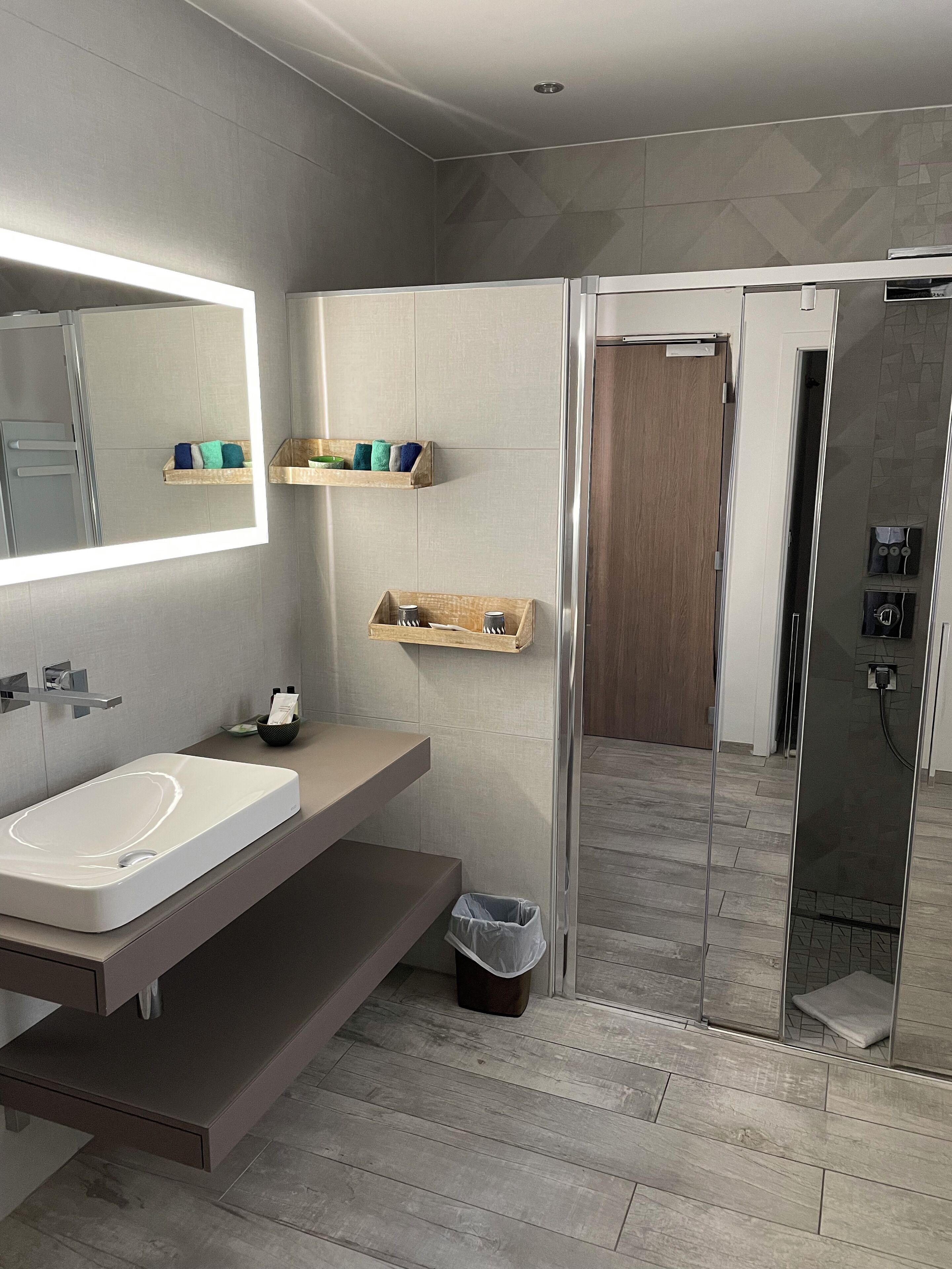Een moderne badkamer met een grote spiegel, een wastafelmeubel met een wastafel en een douchegedeelte.