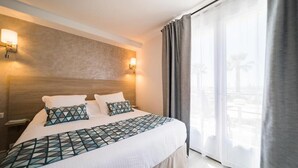 Habitación de hotel con una cama grande, dos lámparas de noche, vistas al exterior y una ventana con cortinas.