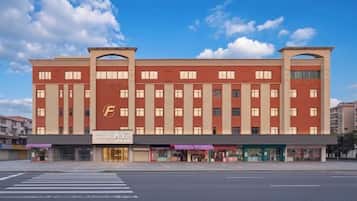 Ett hotell med flera våningar, ett tydligt "F"-logotyp, en central entré och ett övergångsställe framför.