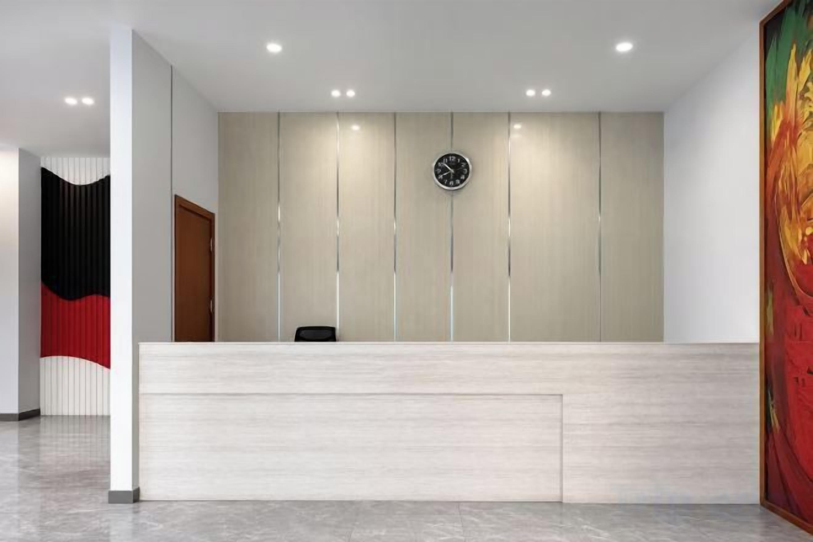 A reception area with a light-colored reception desk, a clock on the wall, and a door to the left.