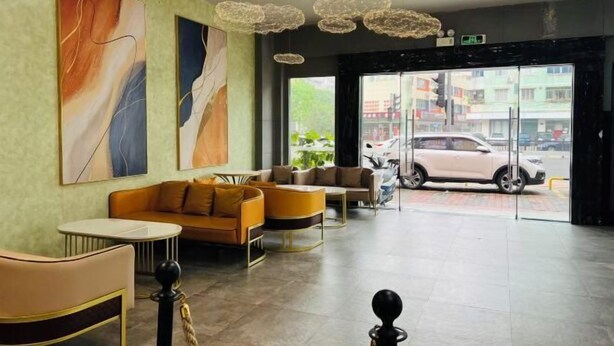A modern lobby with a sofa, chairs, and artwork on the wall. - Fanpo Hotel (Zhongshan)