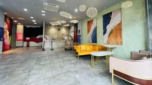 A modern lobby with a reception desk, seating area, and decorative ceiling lights. - Fanpo Hotel (Zhongshan)