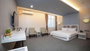 A hotel room with a bed, a desk, two armchairs, a small table, a TV, and a window with curtains. - Fanpo Hotel (Zhongshan)