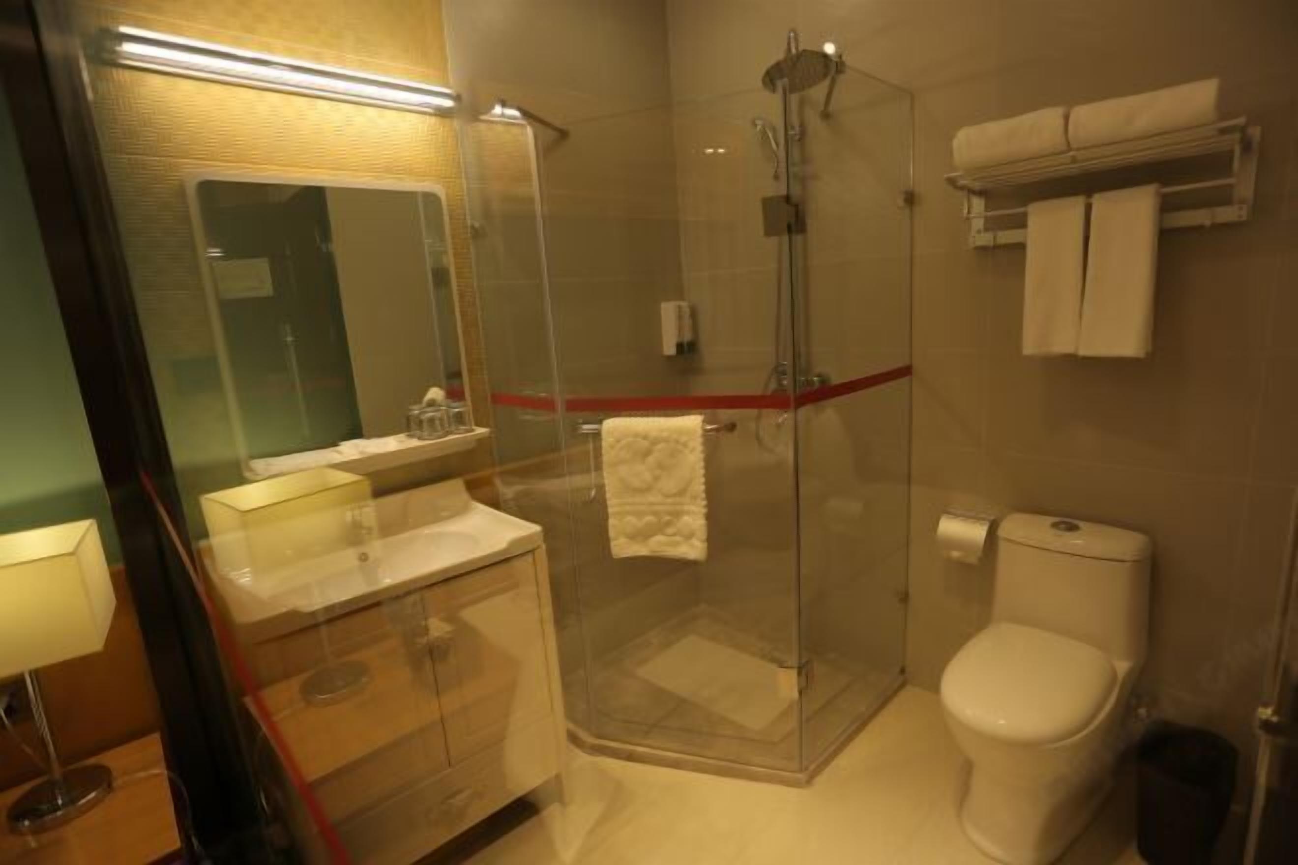 Uma casa de banho moderna com chuveiro envidraçado, sanita, lavatório com espelho e um porta-toalhas.