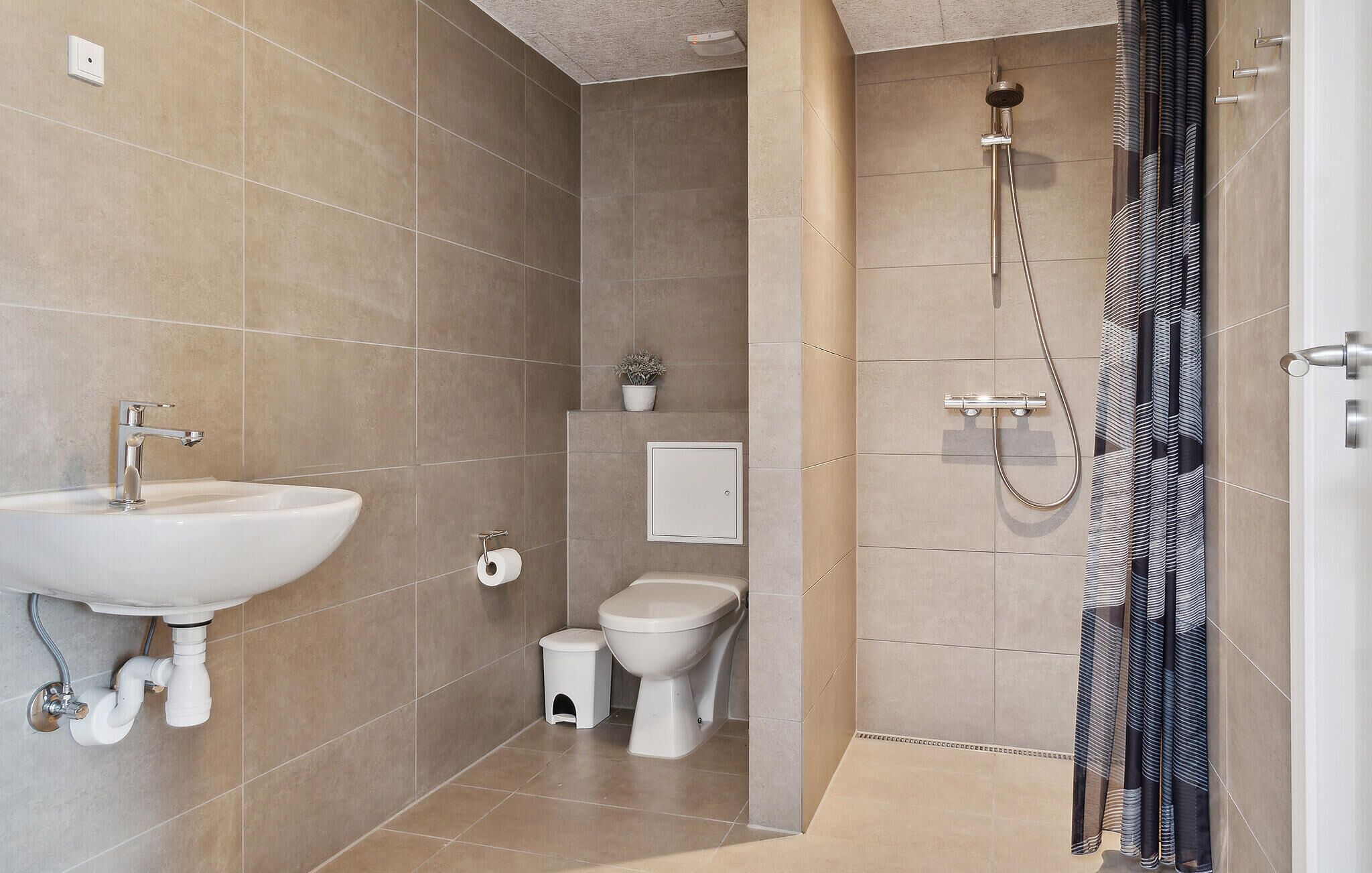 A modern bathroom with a sink, toilet, bidet, and shower.