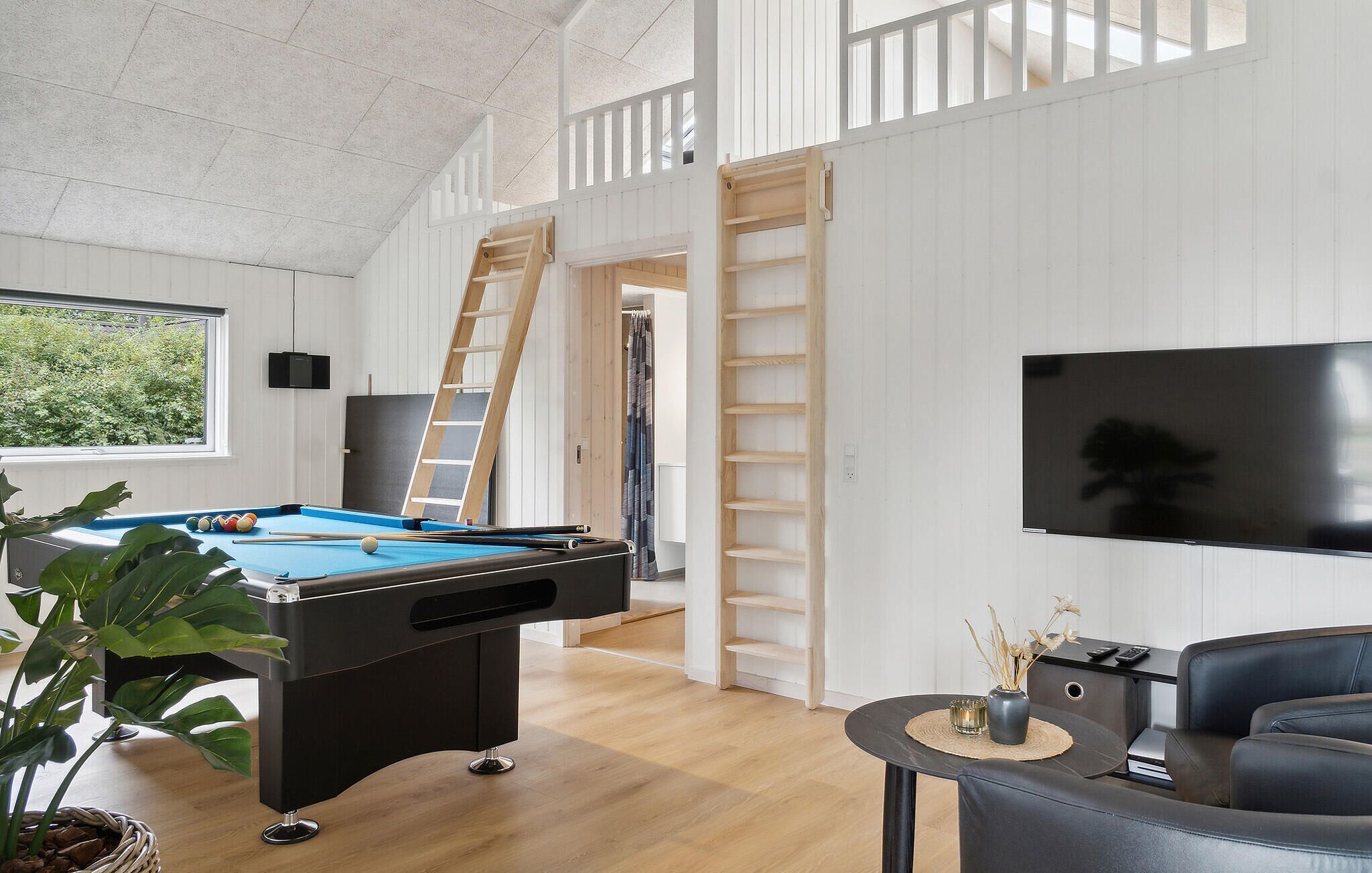A modern living room with a pool table, a TV, and a staircase.