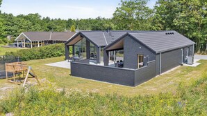 Une maison moderne dotée d’une grande baie vitrée, d’un balcon et d’un jardin.