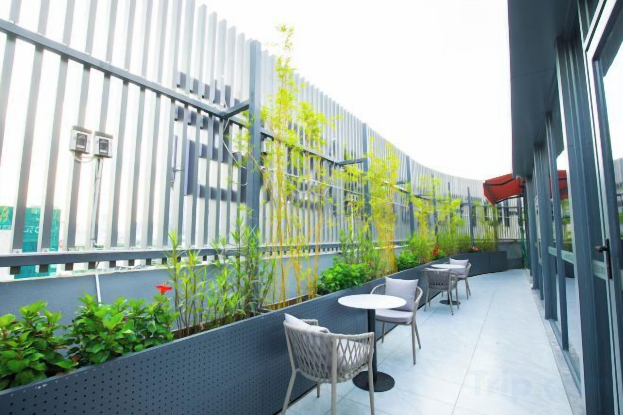 Una terraza en la azotea con mobiliario exterior, una valla de metal y plantas en macetas.