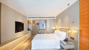 A modern hotel room with a large bed, a flat-screen TV, a bedside table, and a wall-mounted lamp. - Blueprint Cloud Hotel (Shenzhen Longcheng Plaza subway station store) (Shenzhen)