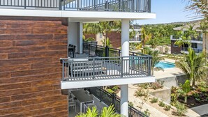 A multi-story building with balconies, outdoor seating, and a pool.