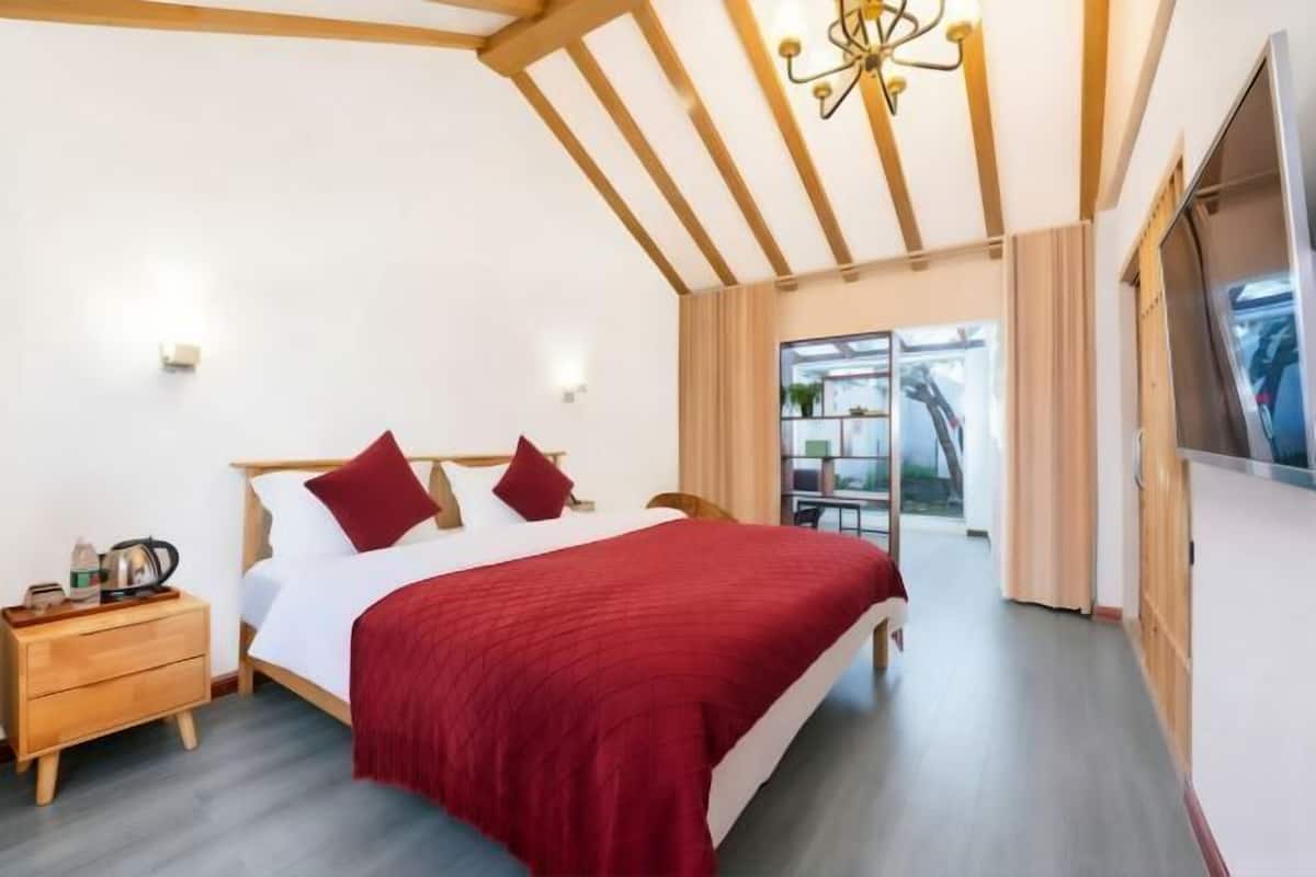 Une chambre à coucher avec un lit, une tête de lit en bois, des tables de chevet et une vue sur l’extérieur.
