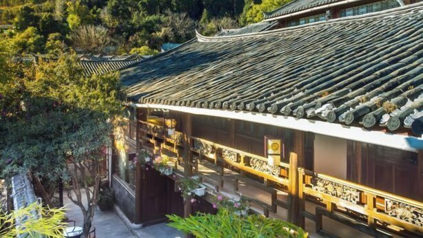 A traditional building with a tiled roof, surrounded by lush greenery and trees. - Qiyue Linyin Bieyuan (Lijiang Gucheng Mufu Branch) (Lijiang)