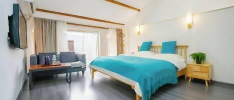 A bedroom with a bed, bedside table, and a seating area with a table and chairs.