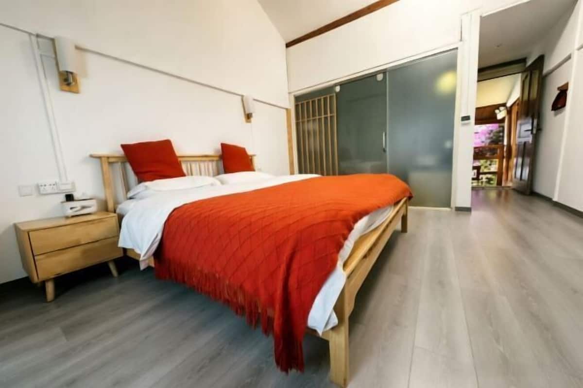 Une chambre à coucher comprenant un lit, une table de chevet et une porte coulissante donnant sur une autre pièce.