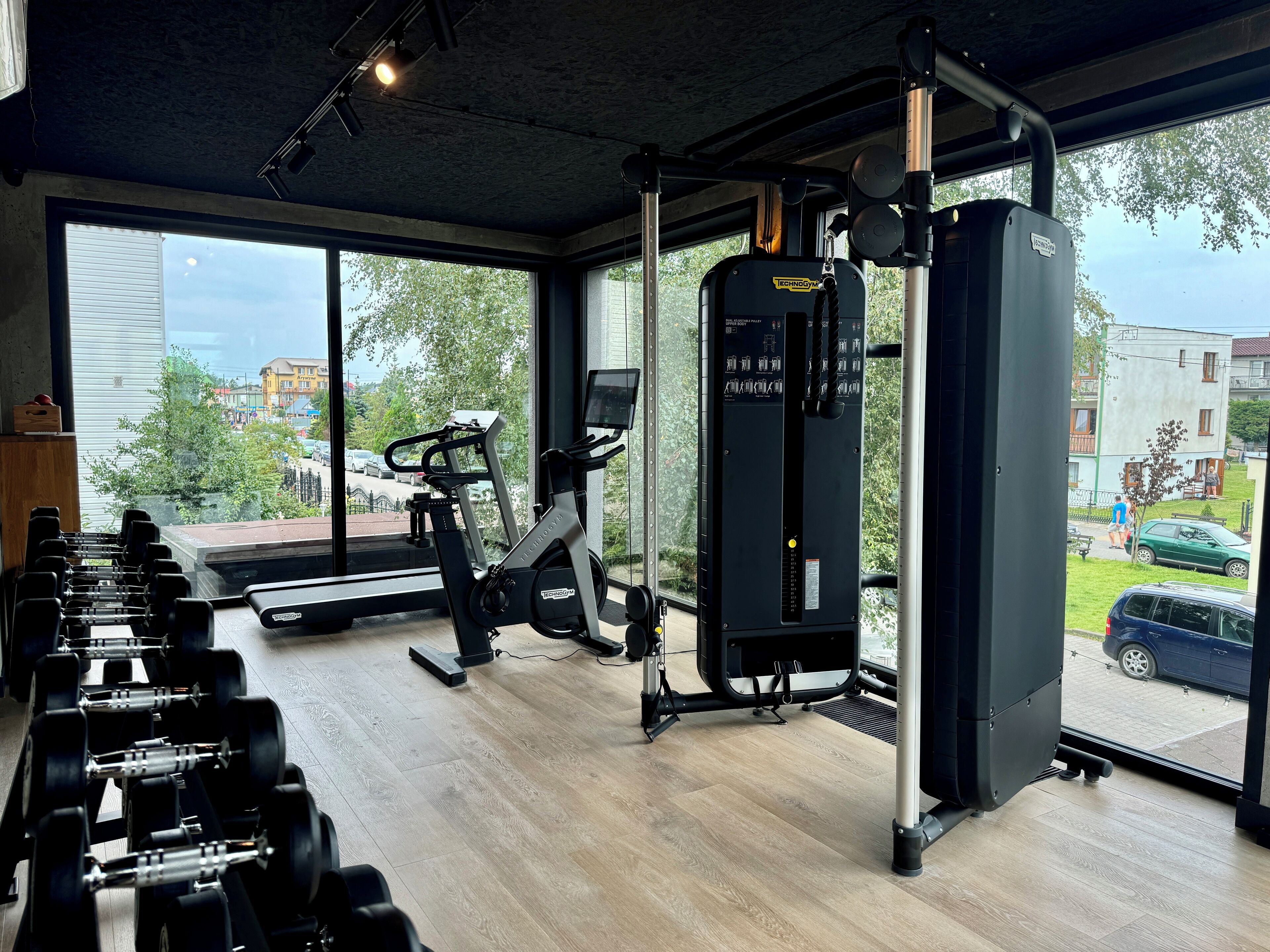 Ett gym med träningsutrustning, stora fönster och utsikt över omgivningen.