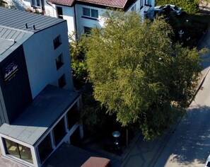 Ein Gebäude mit Flachdach und einem großen Baum davor.