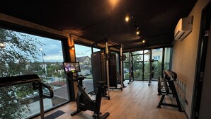 Un gimnasio con equipo cardiovascular, máquinas de pesas y un ventanal con vistas al exterior.