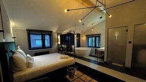 Una habitación de hotel moderna con una cama grande, una zona de estar, una bañera y un televisor.