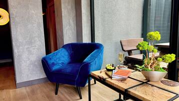 A modern room with a blue velvet chair, a wooden table with a potted plant, and a glass of champagne.