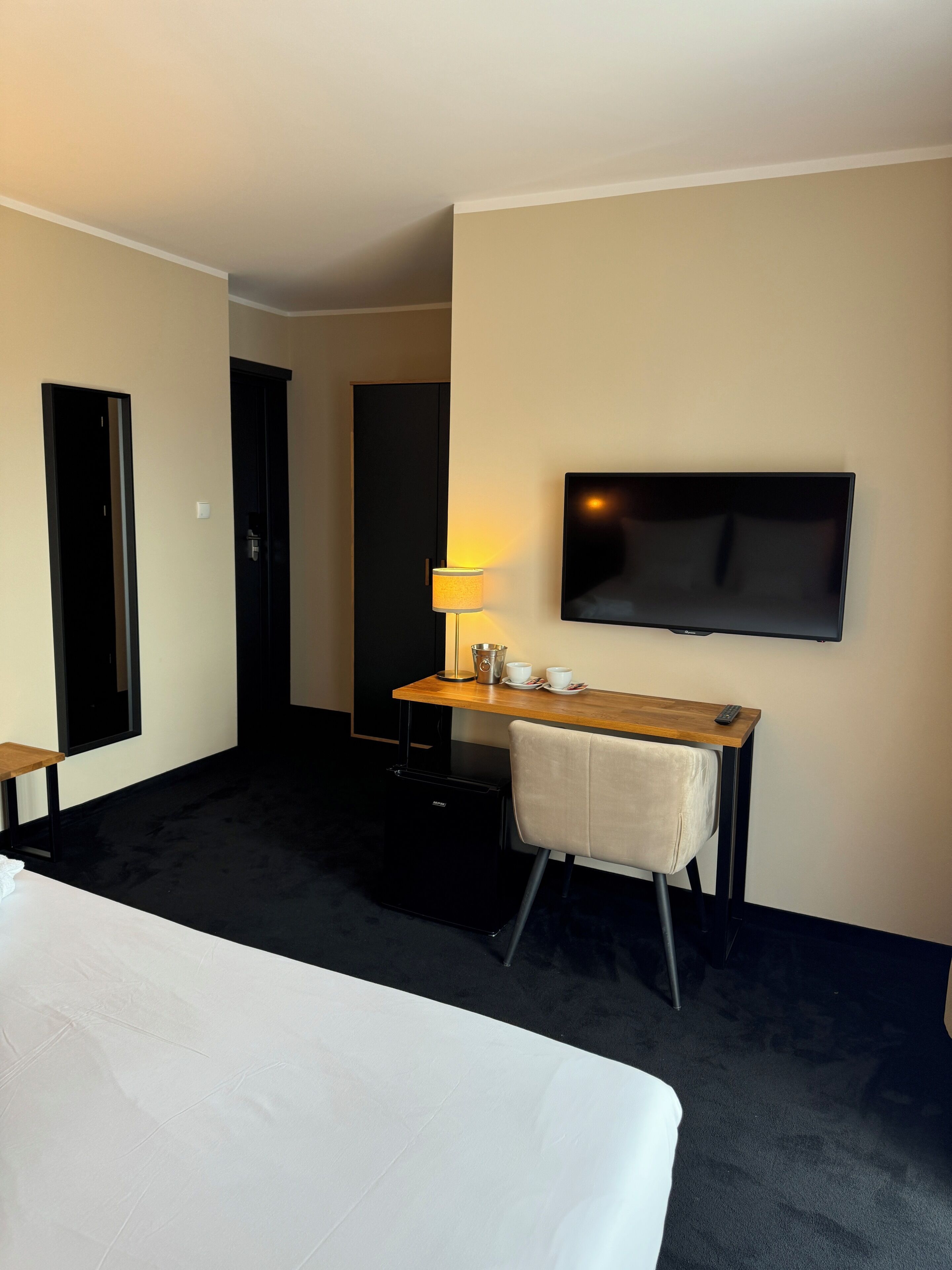 A hotel room with a bed, a desk with a chair, a television, and a coffee maker.