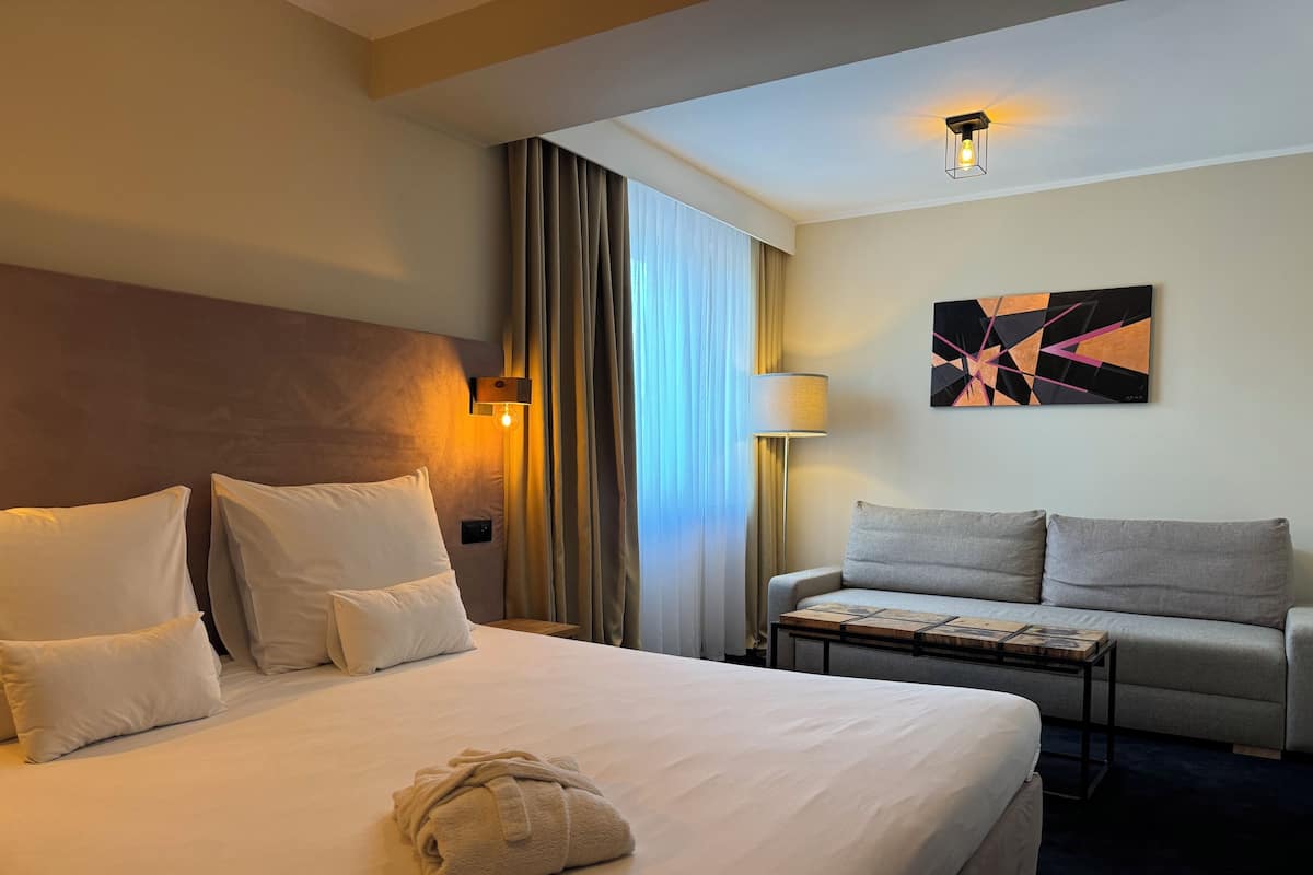 Ein Hotelzimmer mit einem großen Bett, einem Schlafsofa, einem Couchtisch und einem Bild an der Wand.