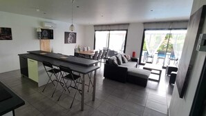 A modern kitchen with a dining area, a sofa, and a view of the outdoors. - Maison de Vacances Avec Piscine - La Maison des Lacs (Lesmont)