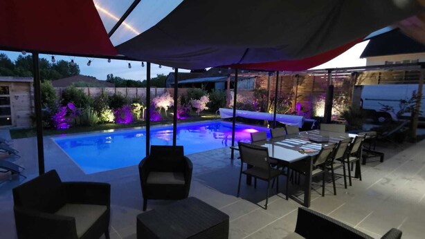 An outdoor pool area with a covered seating area, lounge chairs, and a dining table. - Maison de Vacances Avec Piscine - La Maison des Lacs (Lesmont)