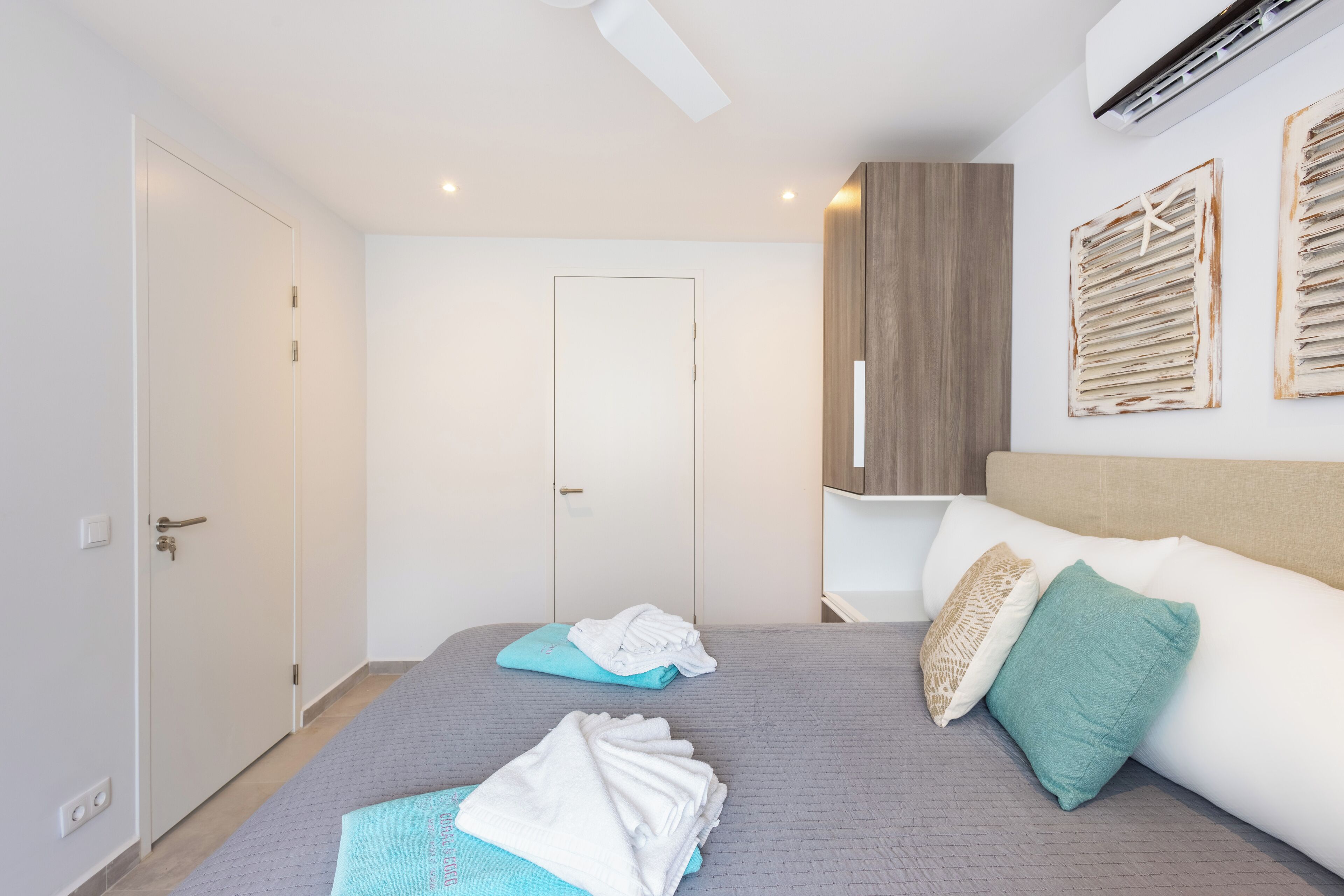 A modern hotel room with a bed, a wardrobe, and a door.