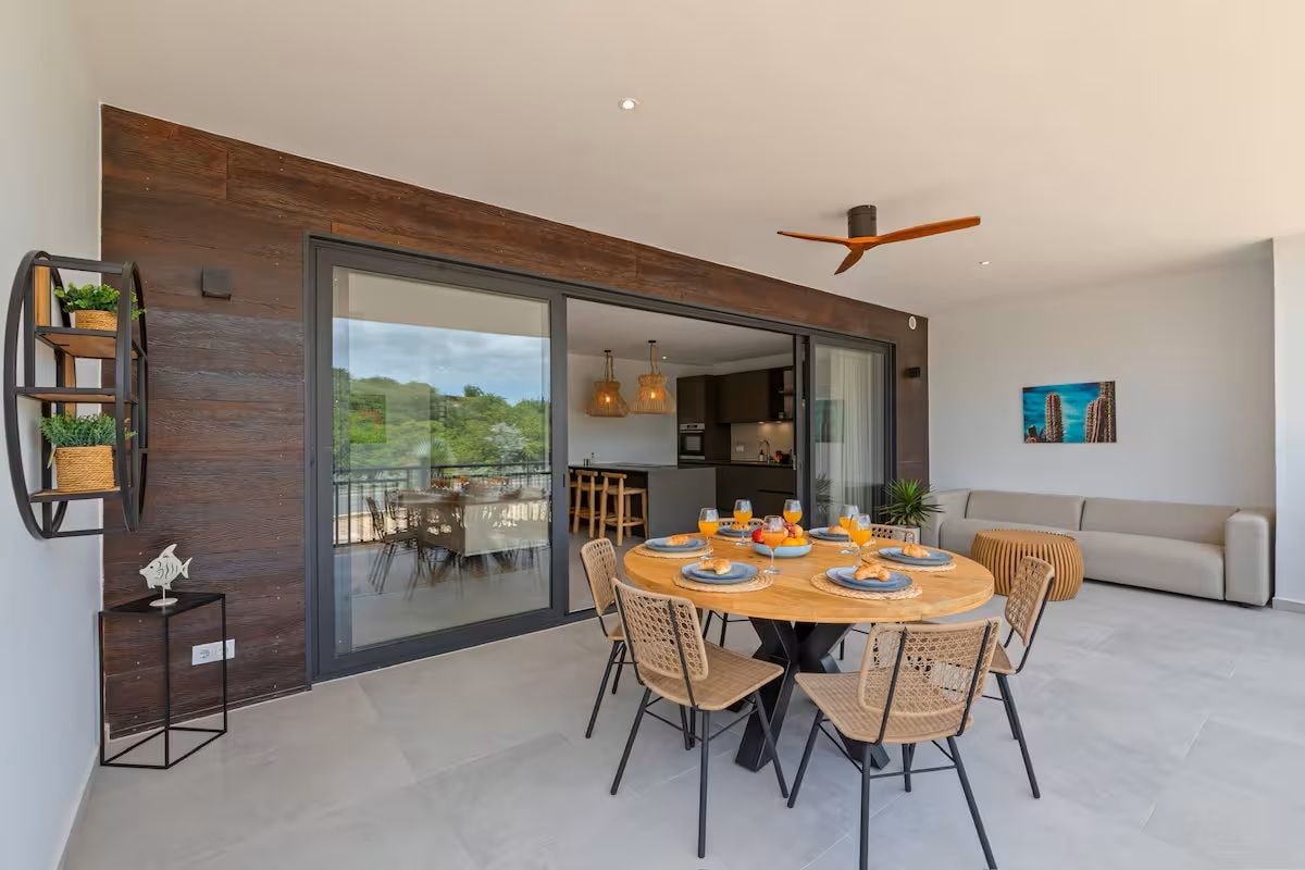 Ett modernt matområde med ett runt bord, stolar och en takfläkt.
