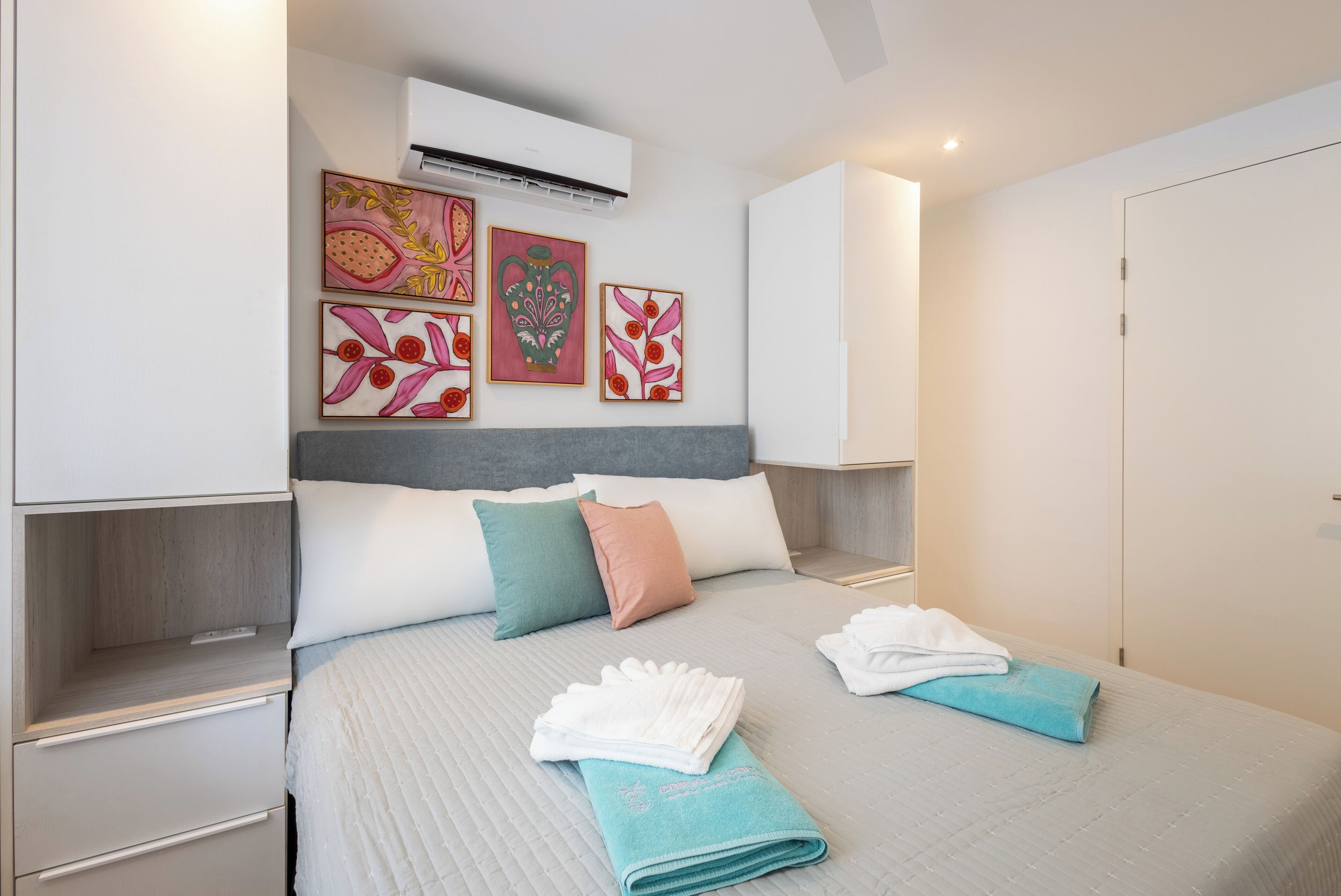 A neatly made bed with pillows, a bedside table, and wall art.