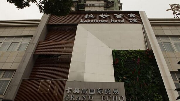 Un hôtel avec une enseigne indiquant « Ludefense Hotel » et « Grand Echo International Trade ».